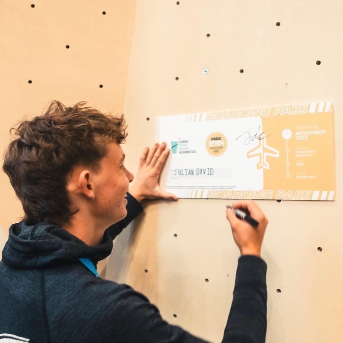 Julian David signs the Paris 2024 boarding pass after winning the Oceania Olympic Qualifier